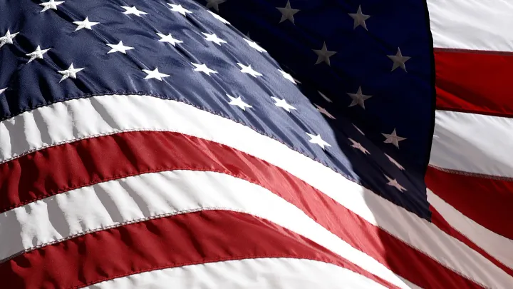 Close-up of a waving American flag showing red and white stripes with white stars on a blue field.